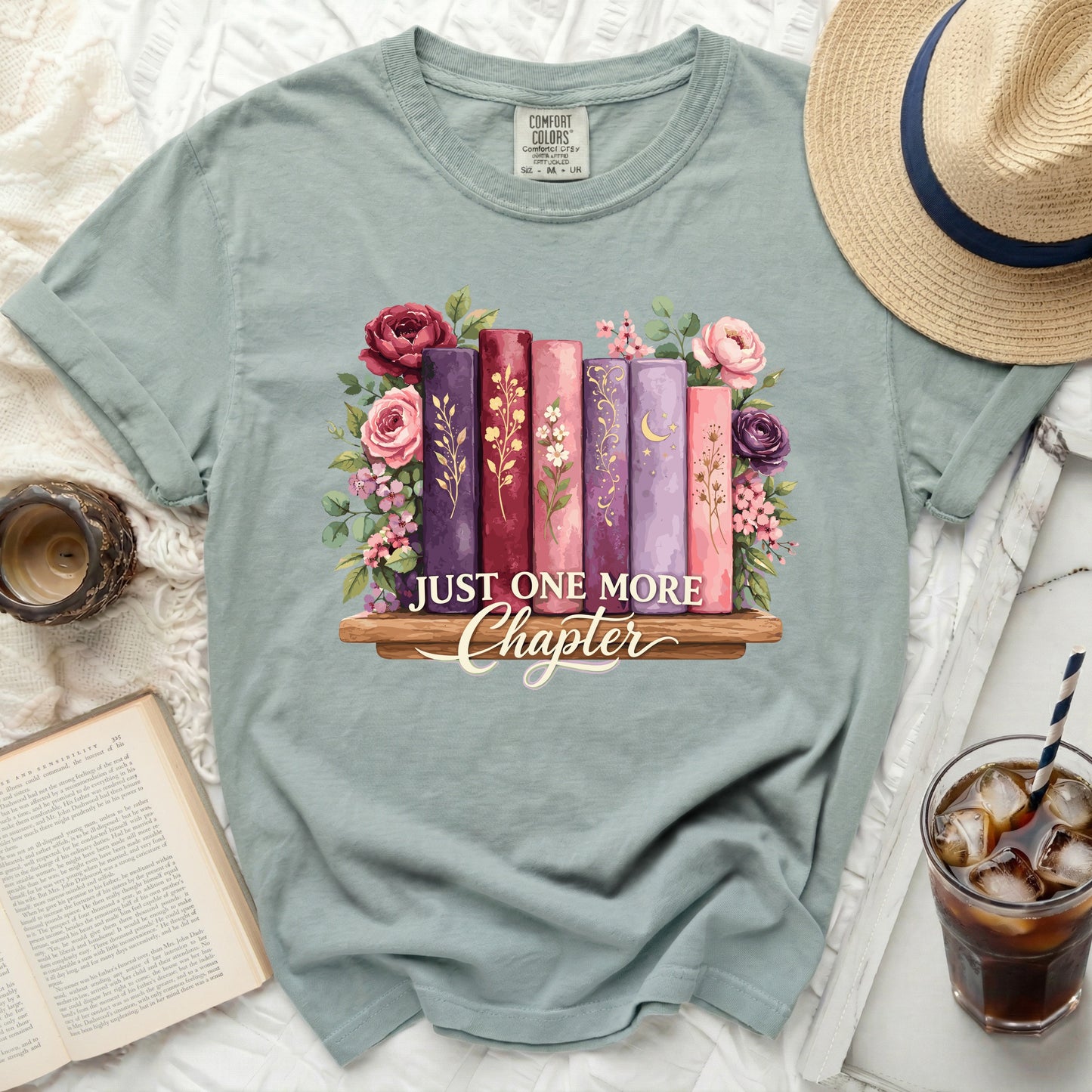 Dusty blue t-shirt with floral books and "Just One More Chapter" text.