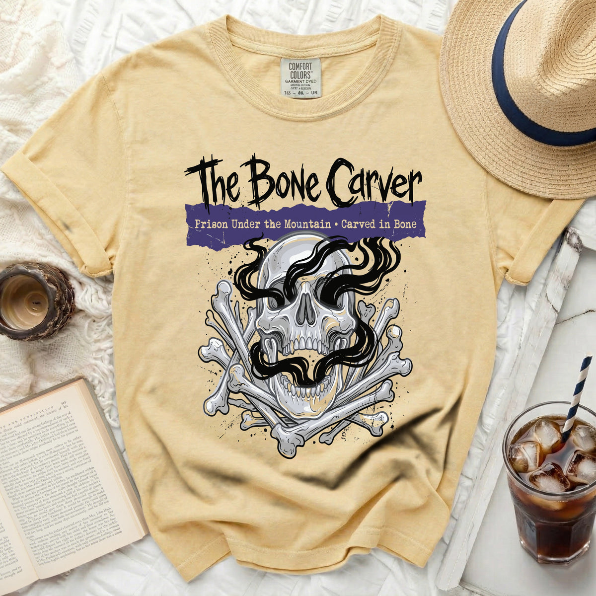 Yellow t-shirt with "The Bone Carver" skull and bones graphic.