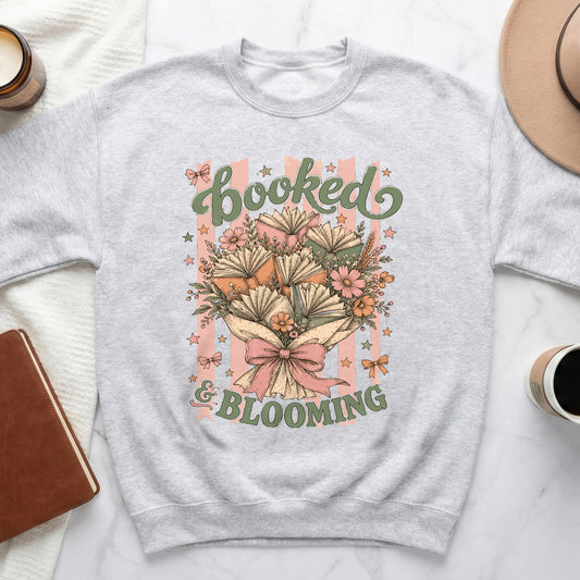 Grey sweatshirt with "Booked & Blooming" text and a bouquet of open books.