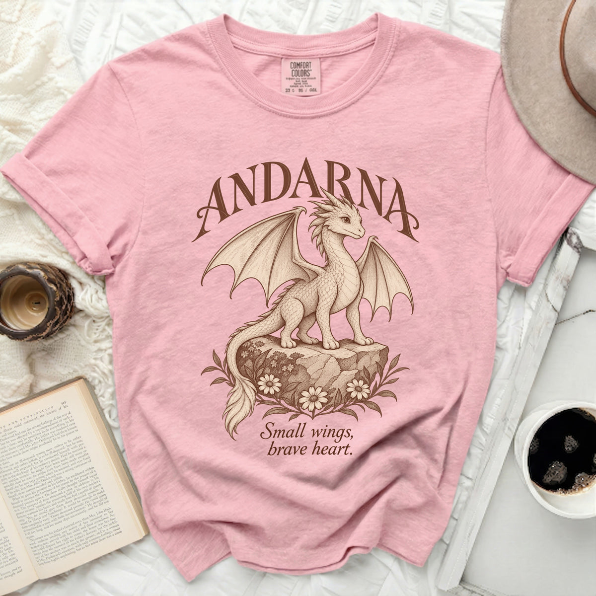 Pink t-shirt with a brown dragon illustration and the text ANDARNA and Small wings brave heart.