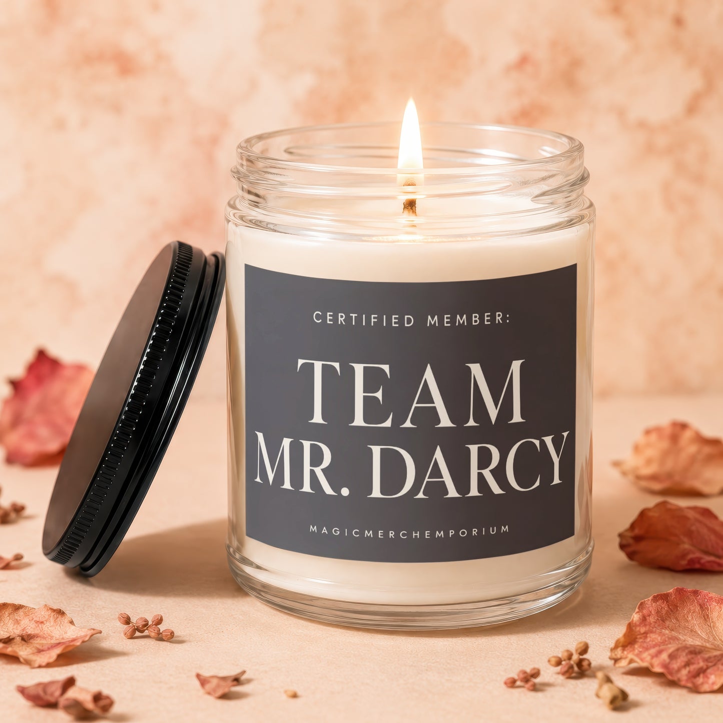 Glass jar candle with "TEAM MR. DARCY" text and a lit wick.