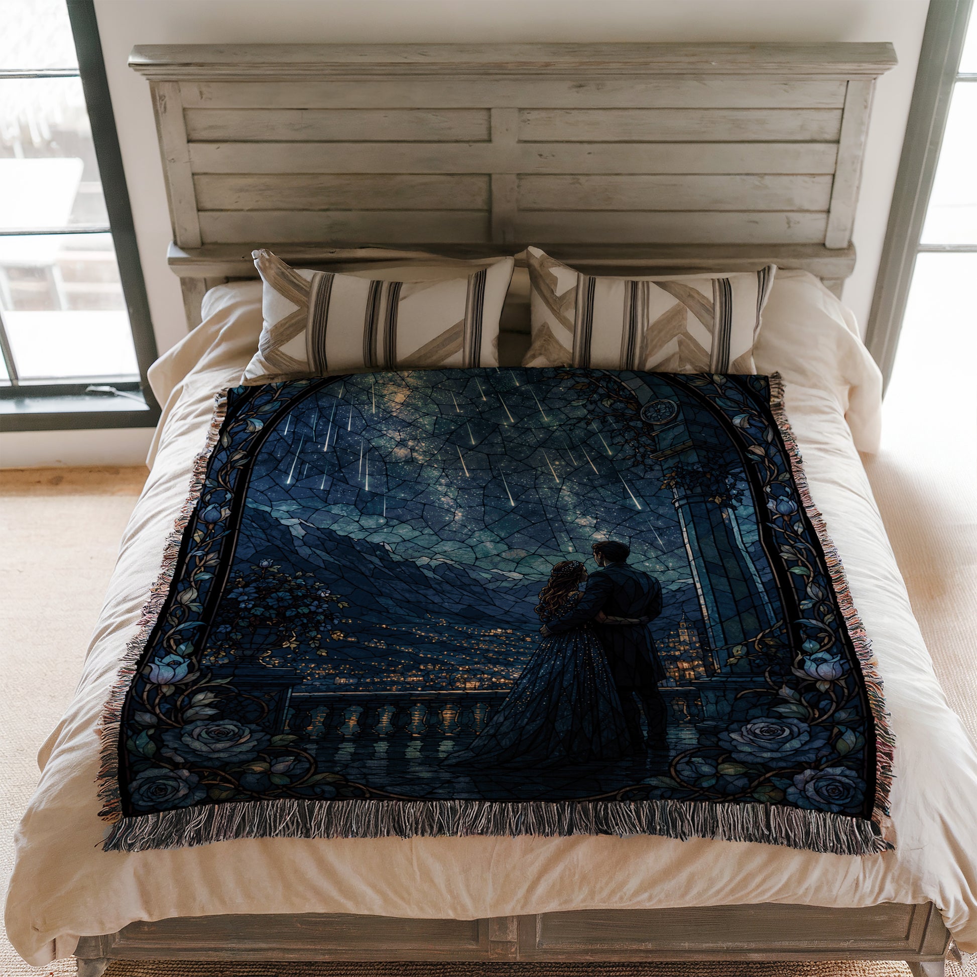 a bed with a decorative blanket featuring a painting of a couple standing together under a starry night sky.