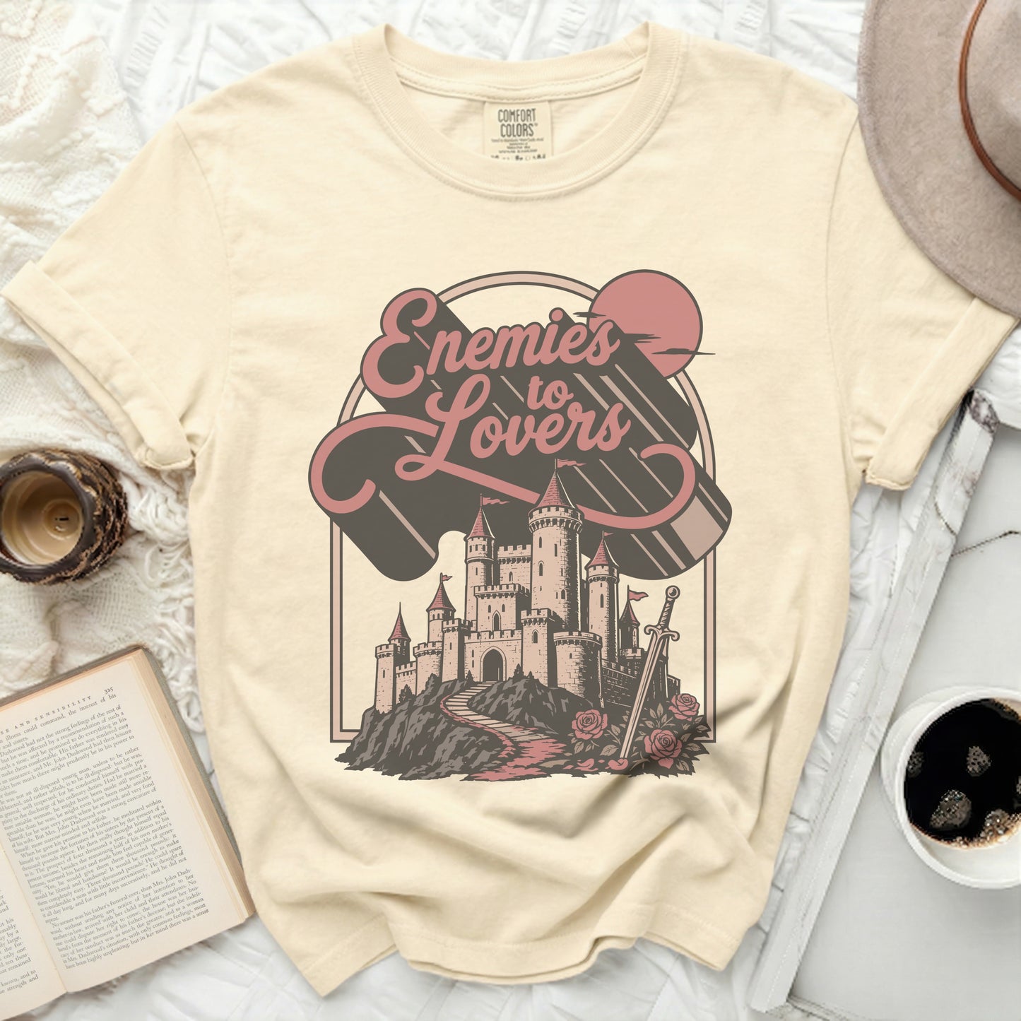 Cream t-shirt with "Enemies to Lovers" text and castle graphic.