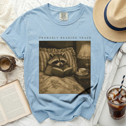 Light blue t-shirt with graphic of raccoon reading "PROBABLY READING TRASH".