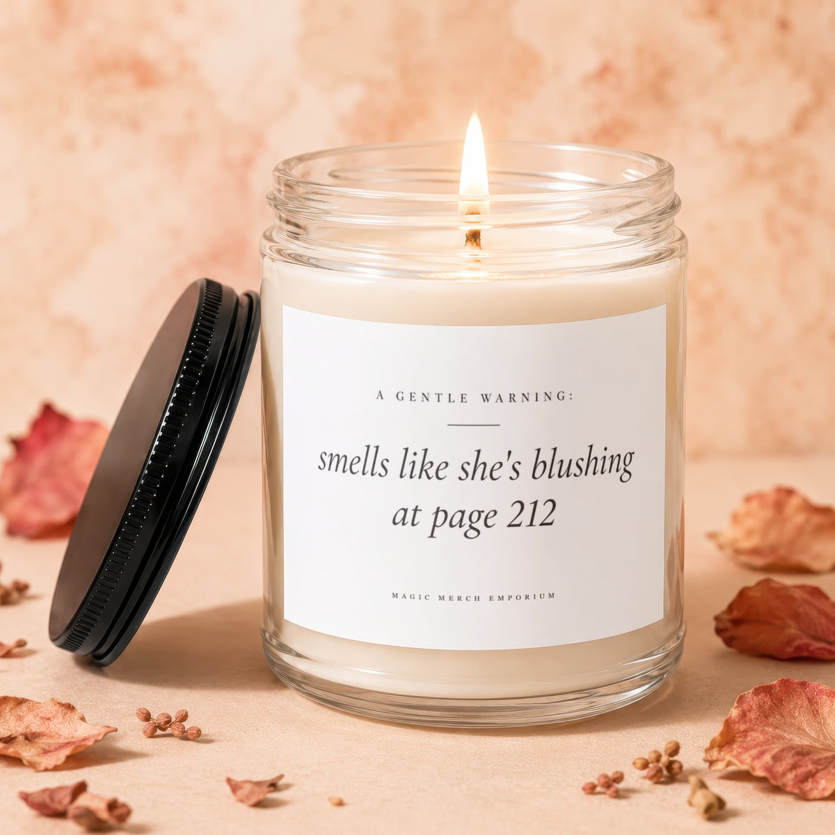 Candle with lit wick, glass jar, and text "smells like she's blushing at page 212".