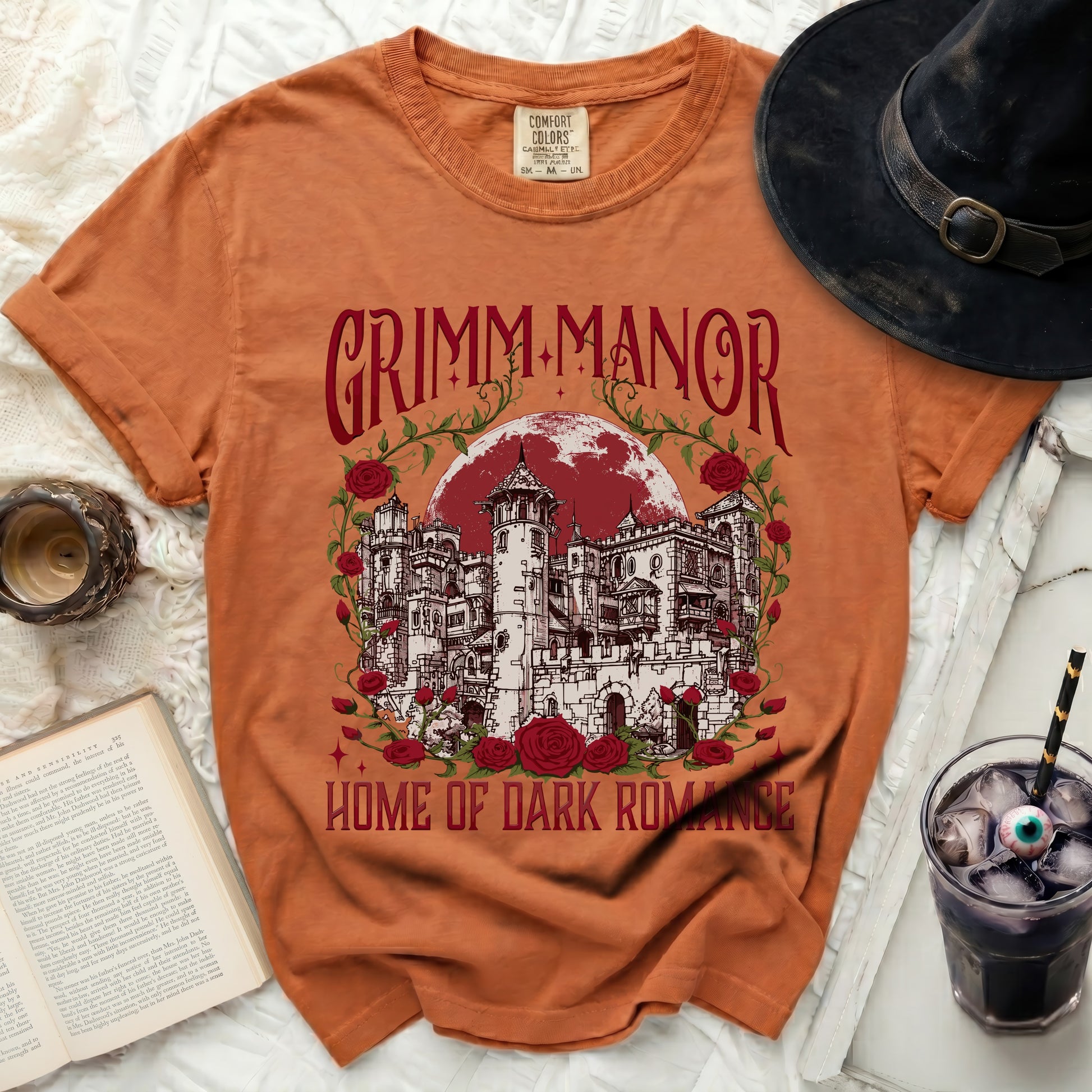 Orange t-shirt with "Grimm Manor Home of Dark Romance" castle graphic.