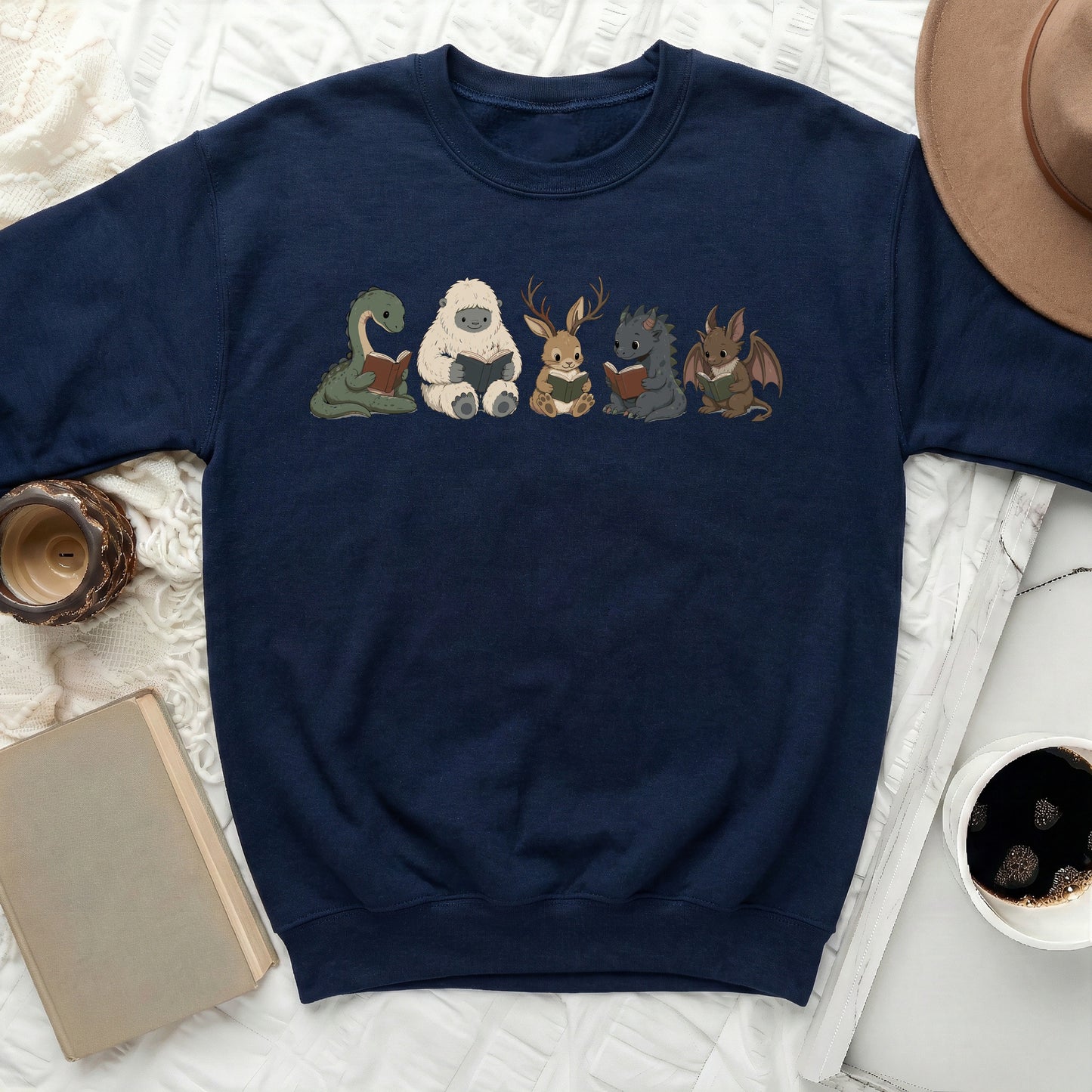 Navy sweatshirt with five cute fantasy creatures reading books.