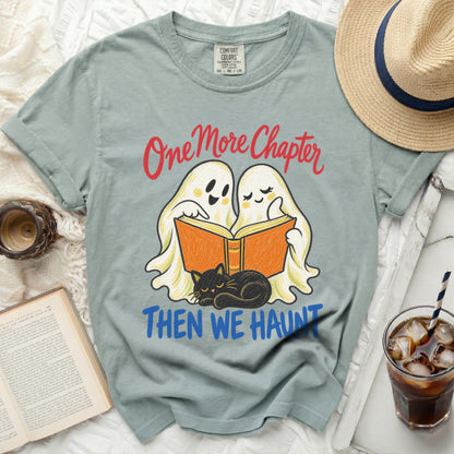 Two cartoon ghosts read a book with a black cat, text "One More Chapter Then We Haunt".