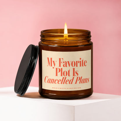 Amber glass candle with lit flame, cream label reads "My Favorite Plot Is Cancelled Plans".