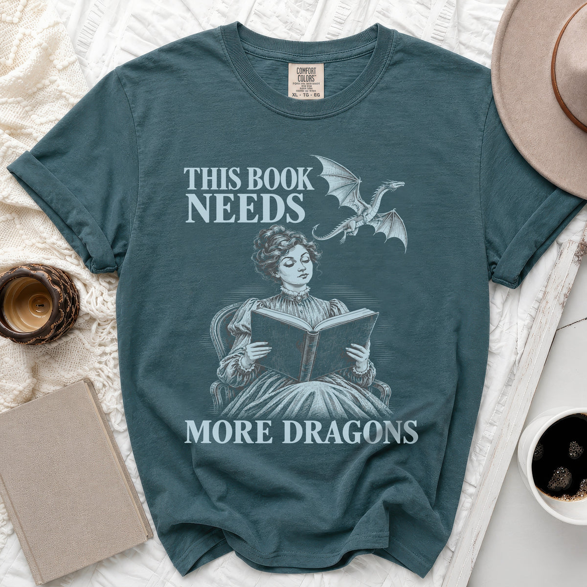 Teal t-shirt with "This Book Needs More Dragons" text and a dragon illustration.