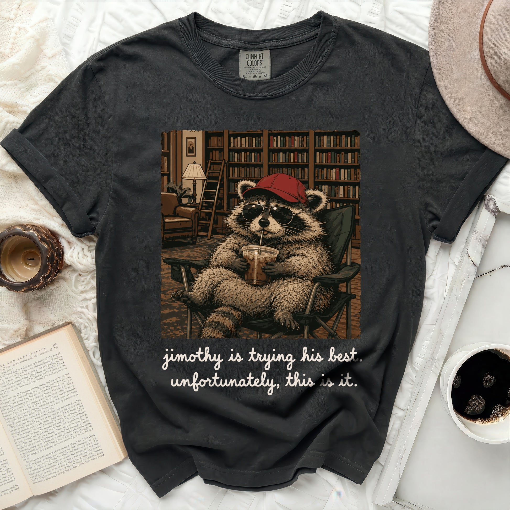 Black t-shirt with a raccoon wearing sunglasses and a hat, holding a drink.