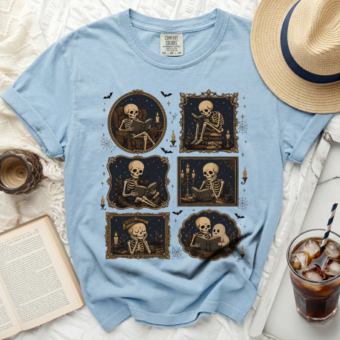 Light blue t-shirt with a print of six framed illustrations of skeletons reading.