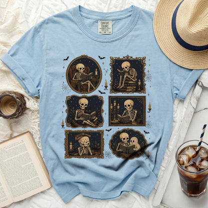 Light blue t-shirt with a print of six framed illustrations of skeletons reading.
