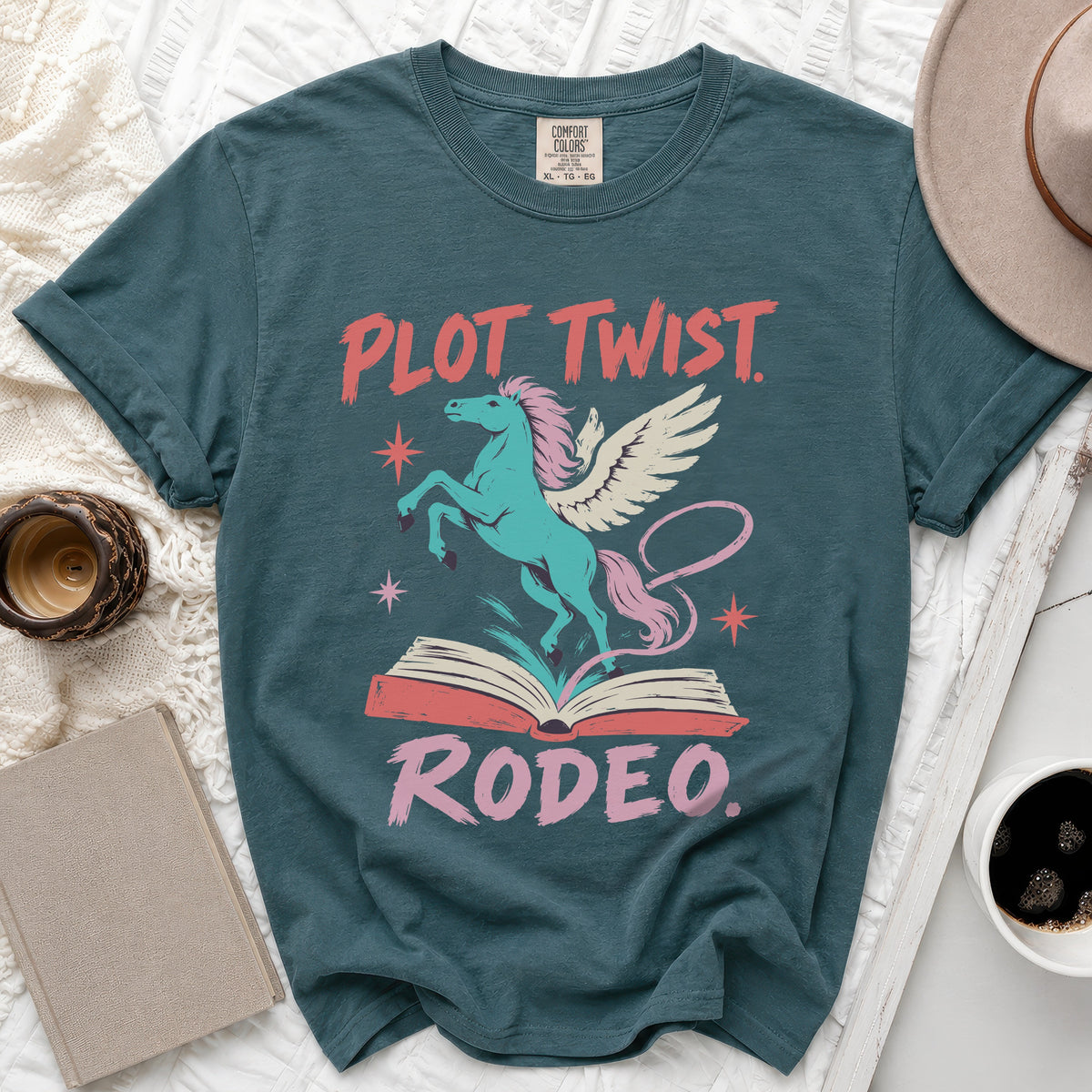 Teal t-shirt with "Plot Twist Rodeo" text and a winged horse above an open book.
