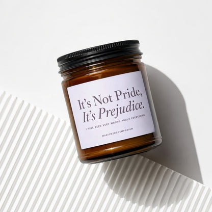 Amber jar candle with black lid reading "It's Not Pride, It's Prejudice."