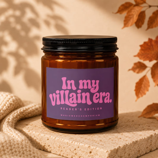 Amber glass candle with black lid and purple label reading "In my villain era. READER'S EDITION MAGICMERCH".