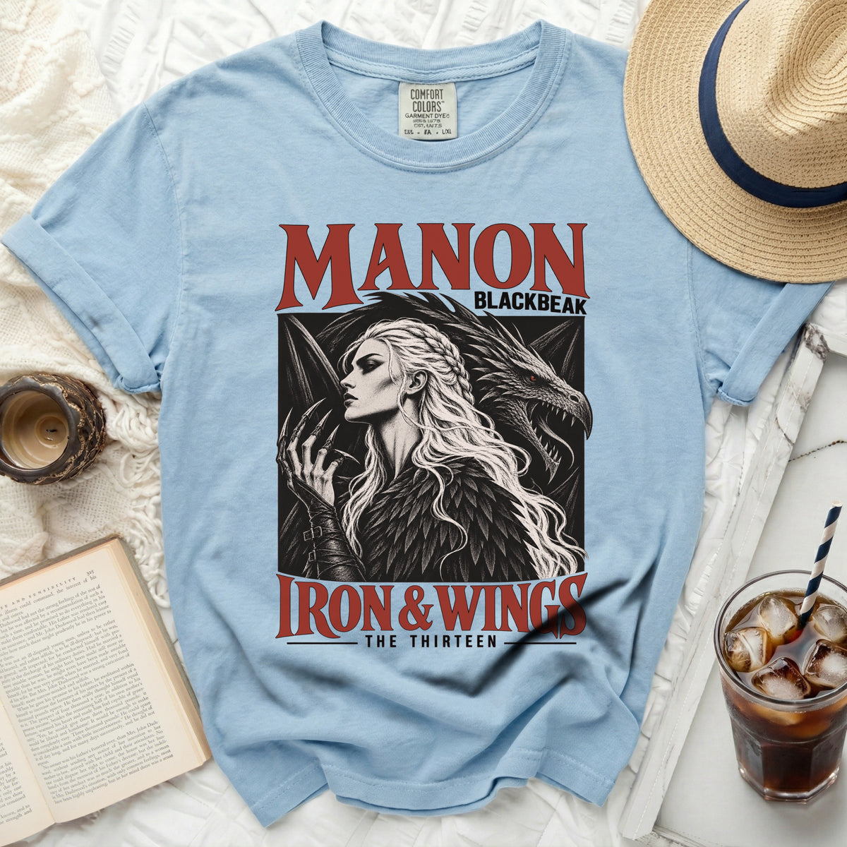 Light blue t-shirt with "Manon Blackbeak Iron & Wings The Thirteen" graphic.
