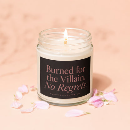 Soy candle with lit wick, dark label text reads "Burned for the Villain. No Regrets."