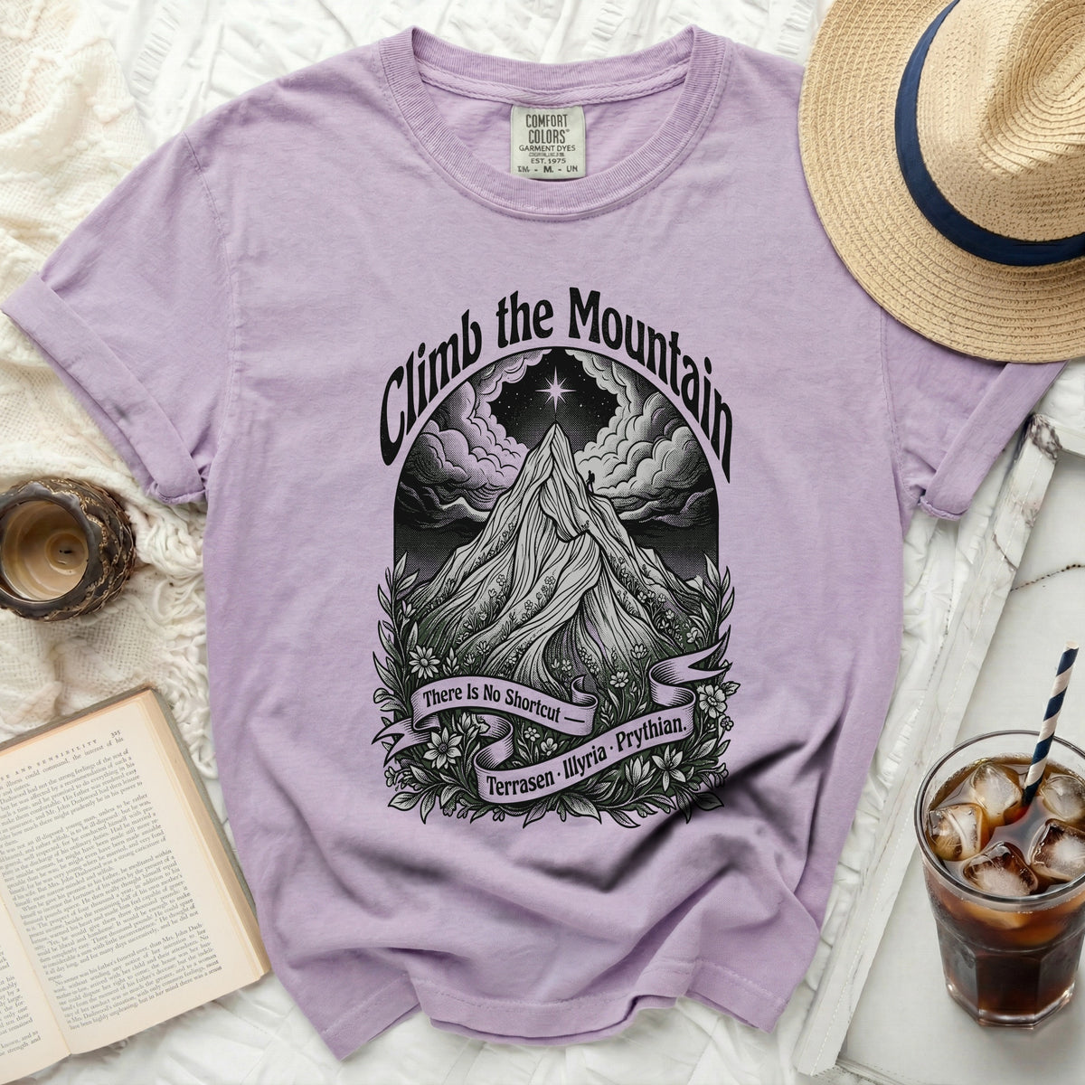 Purple t-shirt with "Climb the Mountain" graphic, featuring a mountain, clouds, and banner.