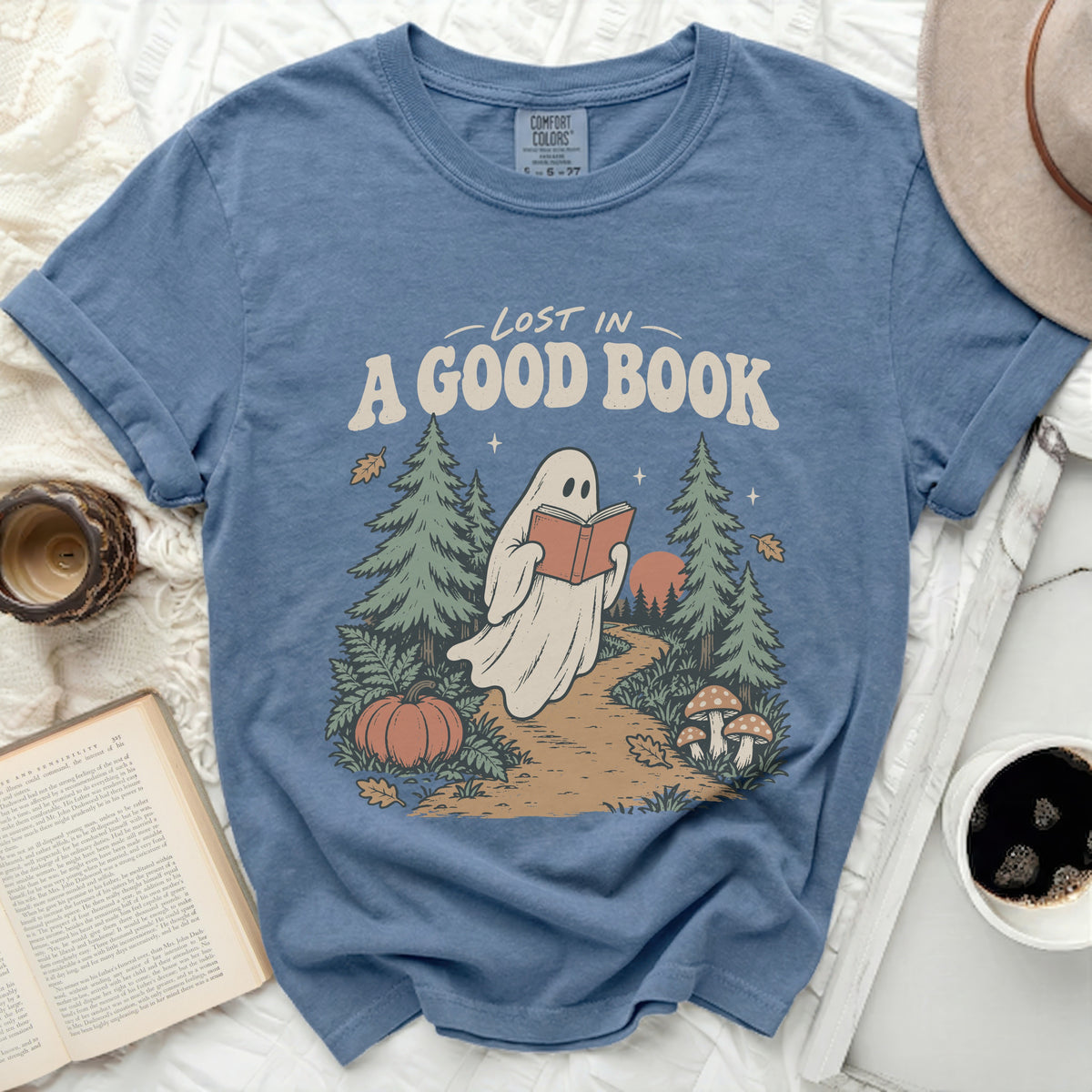 Blue t-shirt with ghost reading "Lost in a good book" graphic, trees, pumpkin, mushrooms.