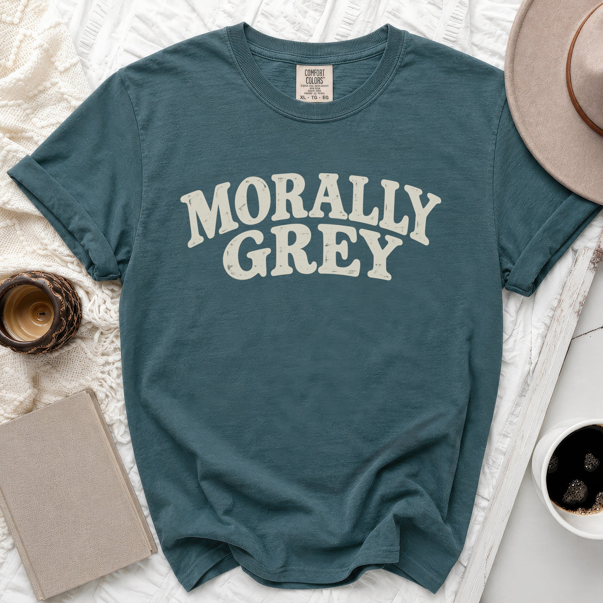 Teal t-shirt with "MORALLY GREY" text, Comfort Colors tag, and book.