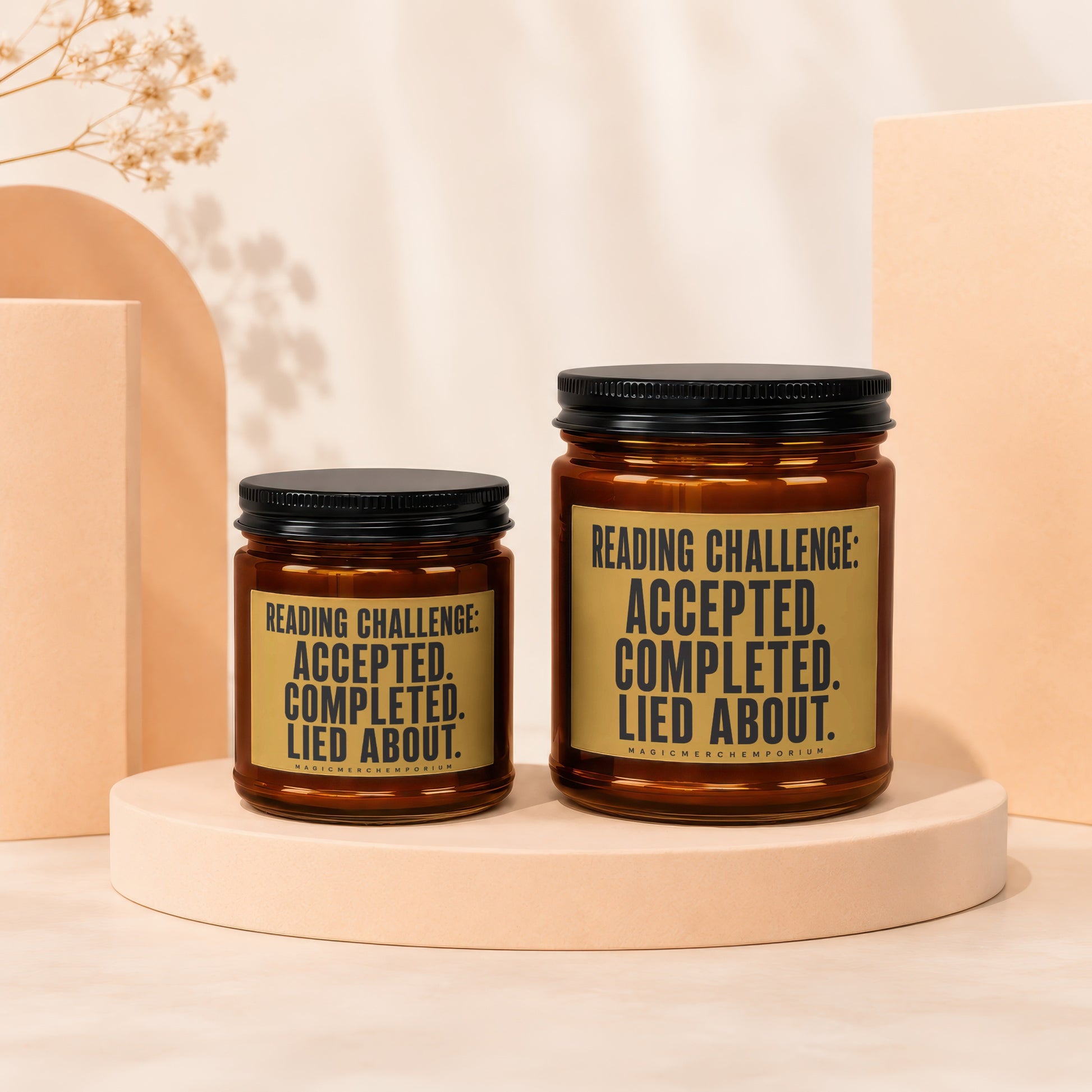 Two amber candles with black lids displaying "Reading Challenge: Accepted. Completed. Lied About."
