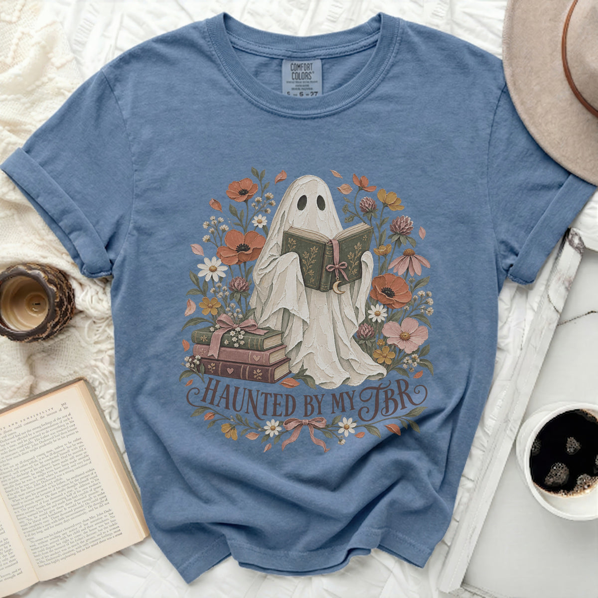 Ghost reading book surrounded by flowers, with text "Haunted by my TBR".