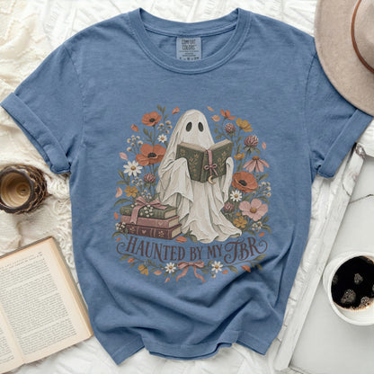 Ghost reading book surrounded by flowers, with text "Haunted by my TBR".