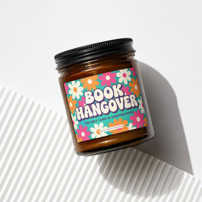 Amber jar candle with "Book Hangover" and flower design label.