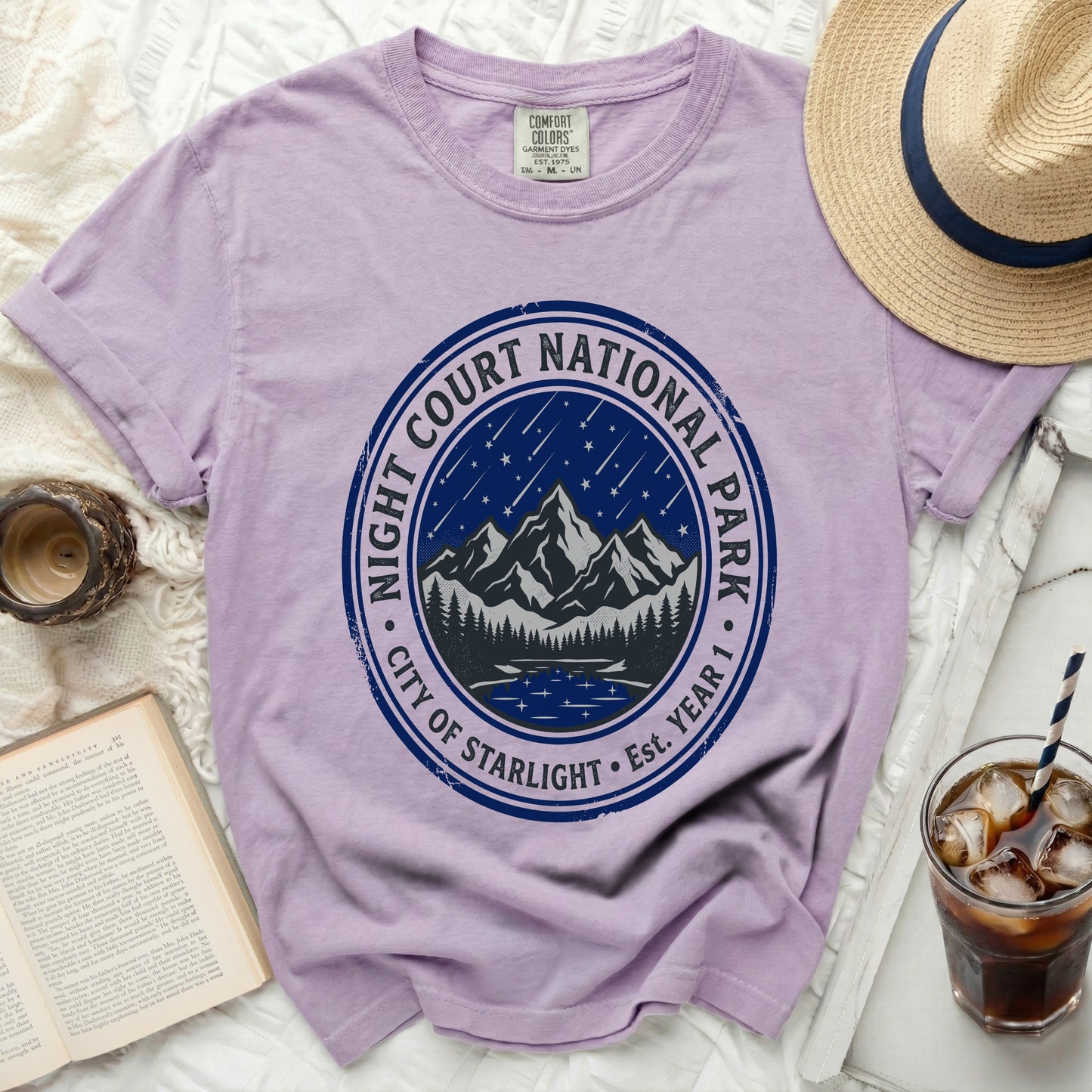 Lavender t-shirt with a circular graphic of mountains, lake, and stars.