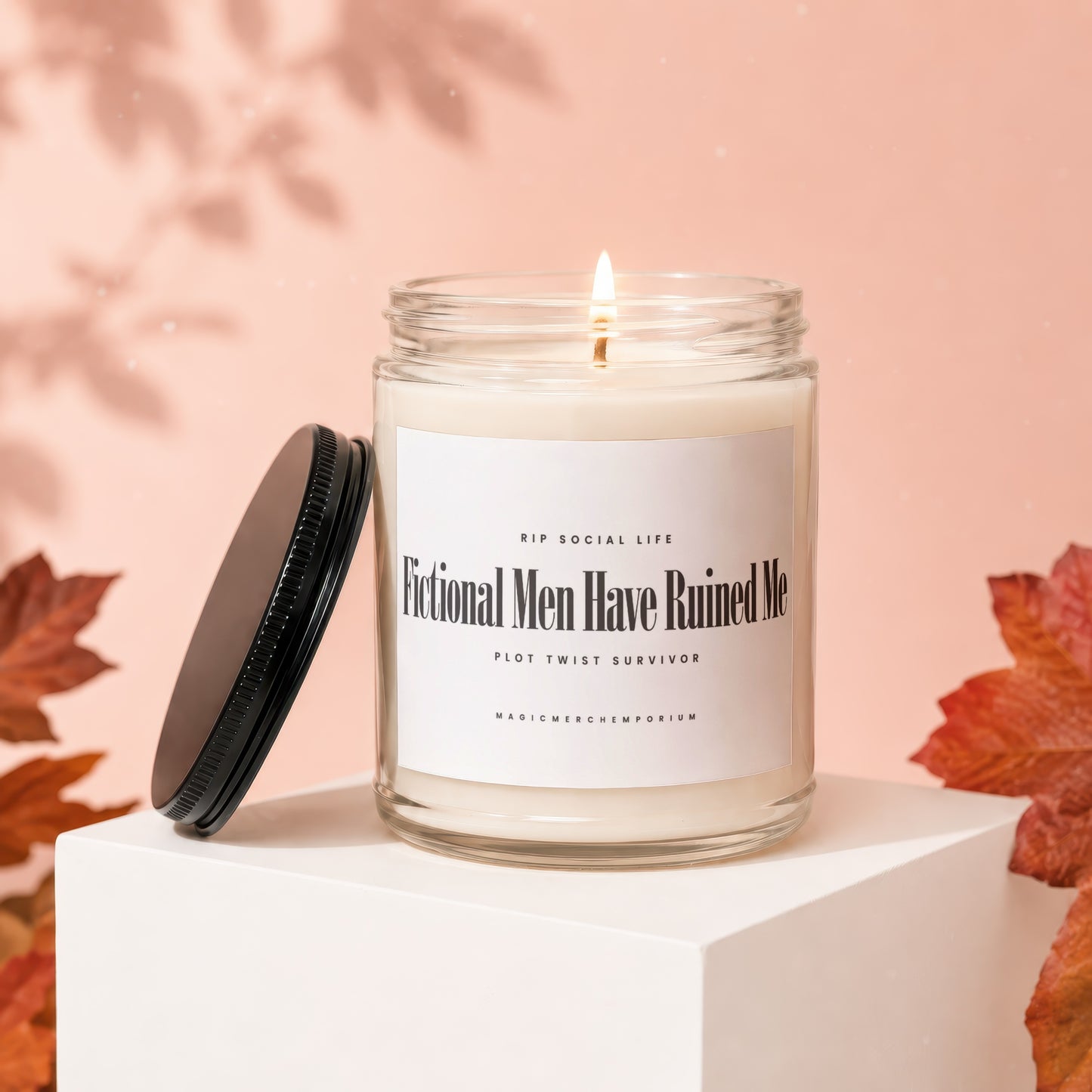 Candle with "Fictional Men Have Ruined Me" text, lit and on a pedestal.