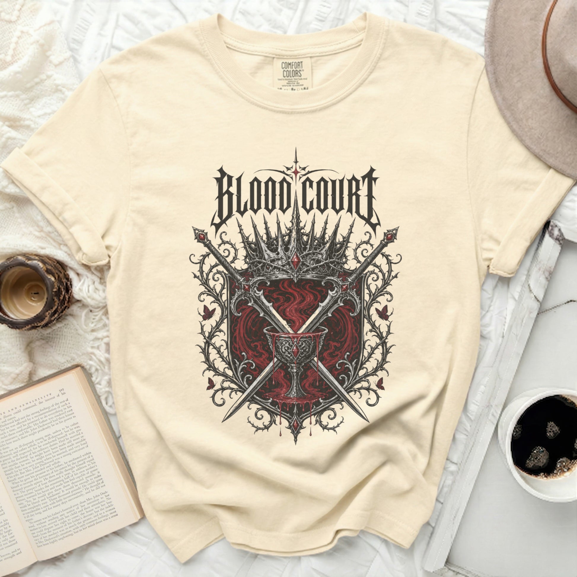 Cream t-shirt with "Blood Court" text and gothic crown and sword emblem.