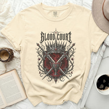 Cream t-shirt with "Blood Court" text and gothic crown and sword emblem.