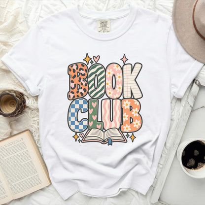 White t-shirt with "Book Club" text in retro fonts and patterns.