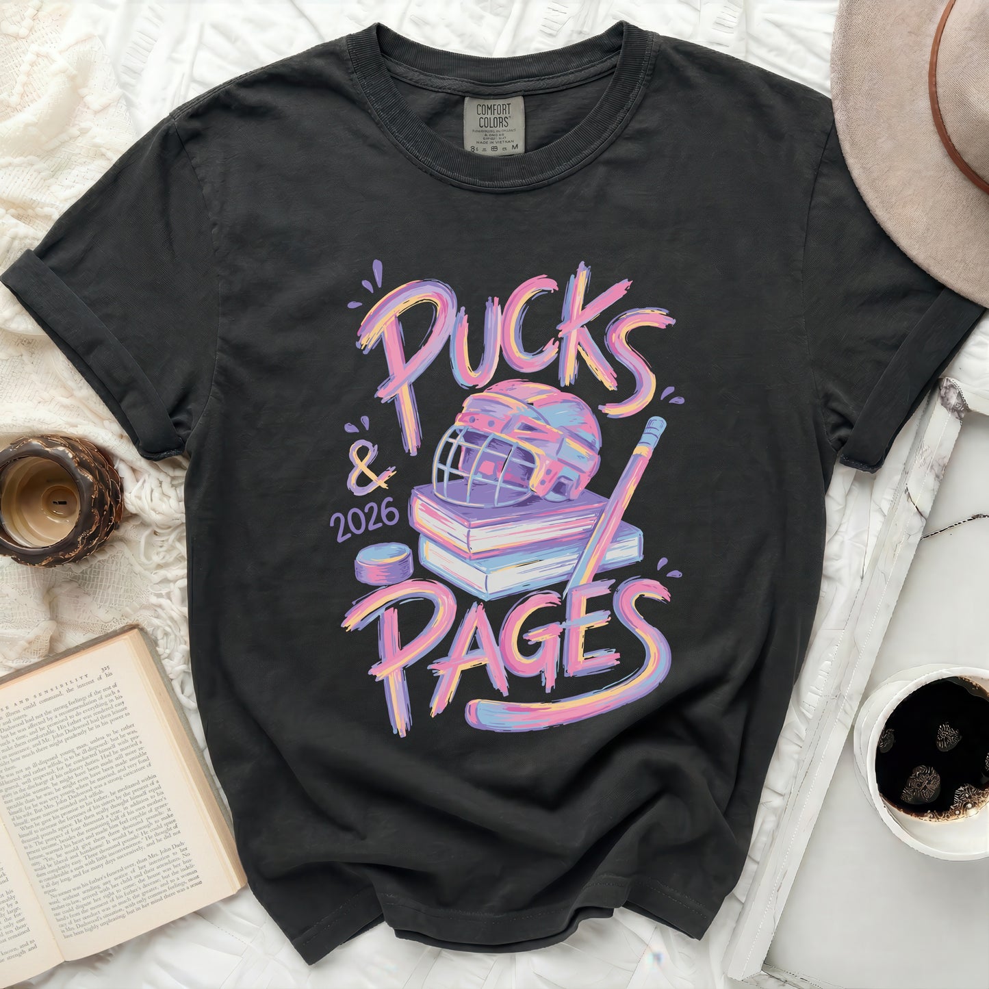 T-shirt with "Pucks & 2026 PAGES" text, hockey puck, and books.