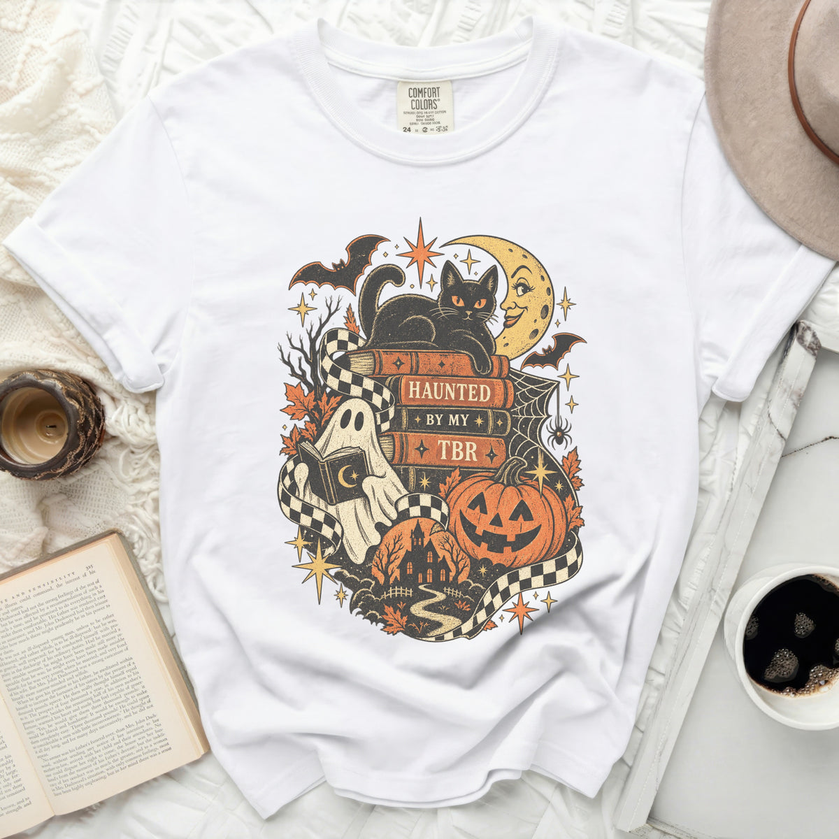 White t-shirt with Halloween-themed graphic of books, black cat, and ghost.