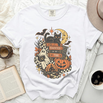 White t-shirt with Halloween-themed graphic of books, black cat, and ghost.