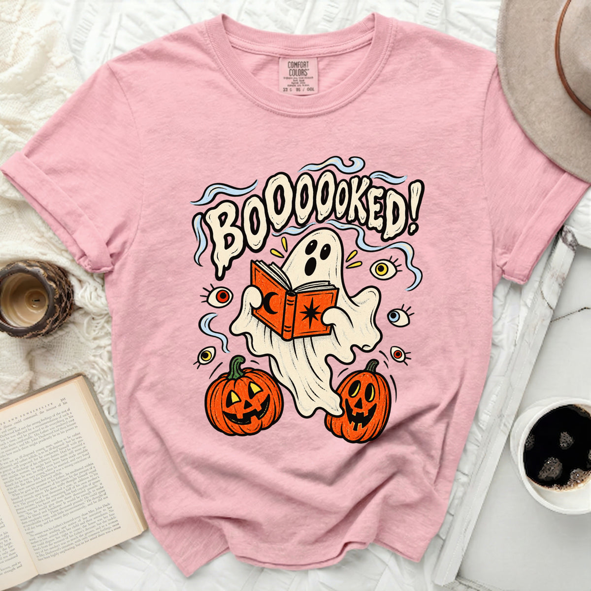 Pink t-shirt with ghost reading book and pumpkins graphic.