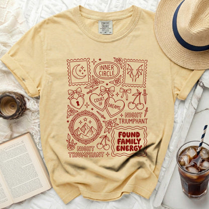 Yellow t-shirt with red graphic elements and text: Inner Circle, Court of Dreams, Night Triumphant, Found Family Energy.
