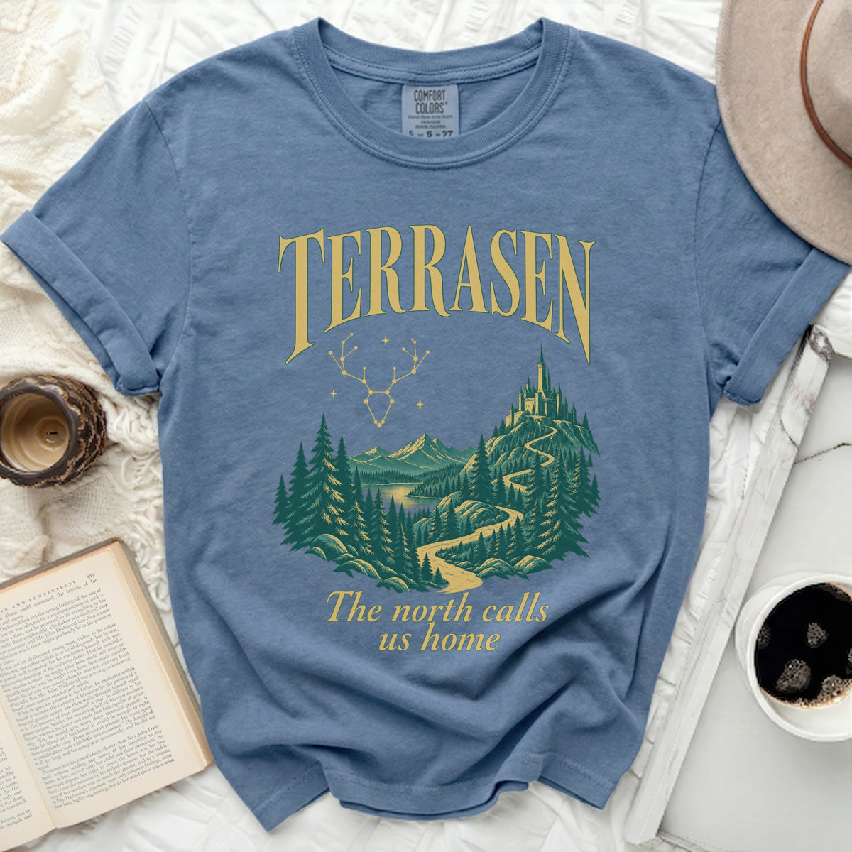 Terrasen graphic t-shirt with mountains, castle, and trees, and text "The north calls us home".