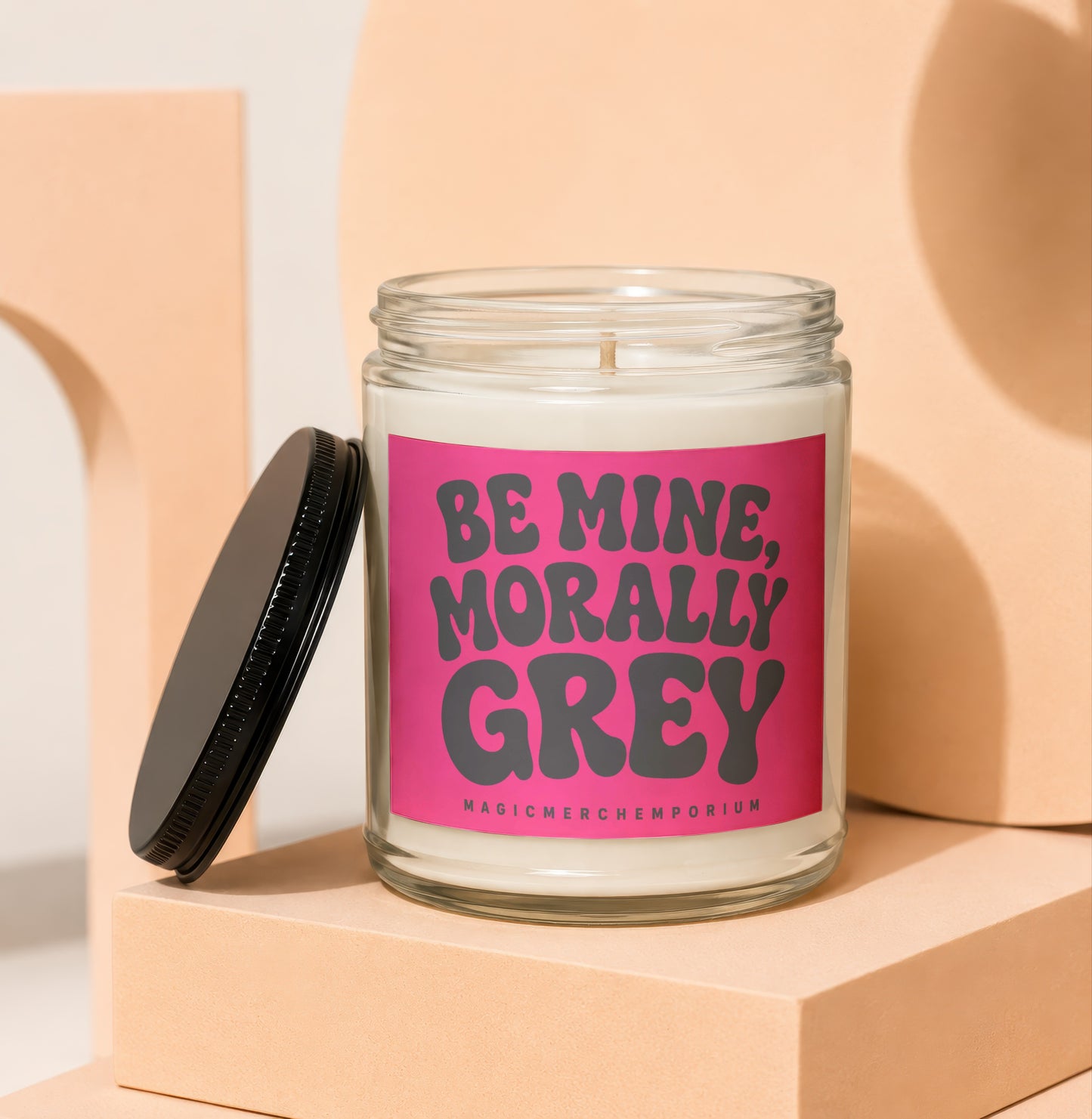 Glass jar candle with pink label that reads "BE MINE, MORALLY GREY".