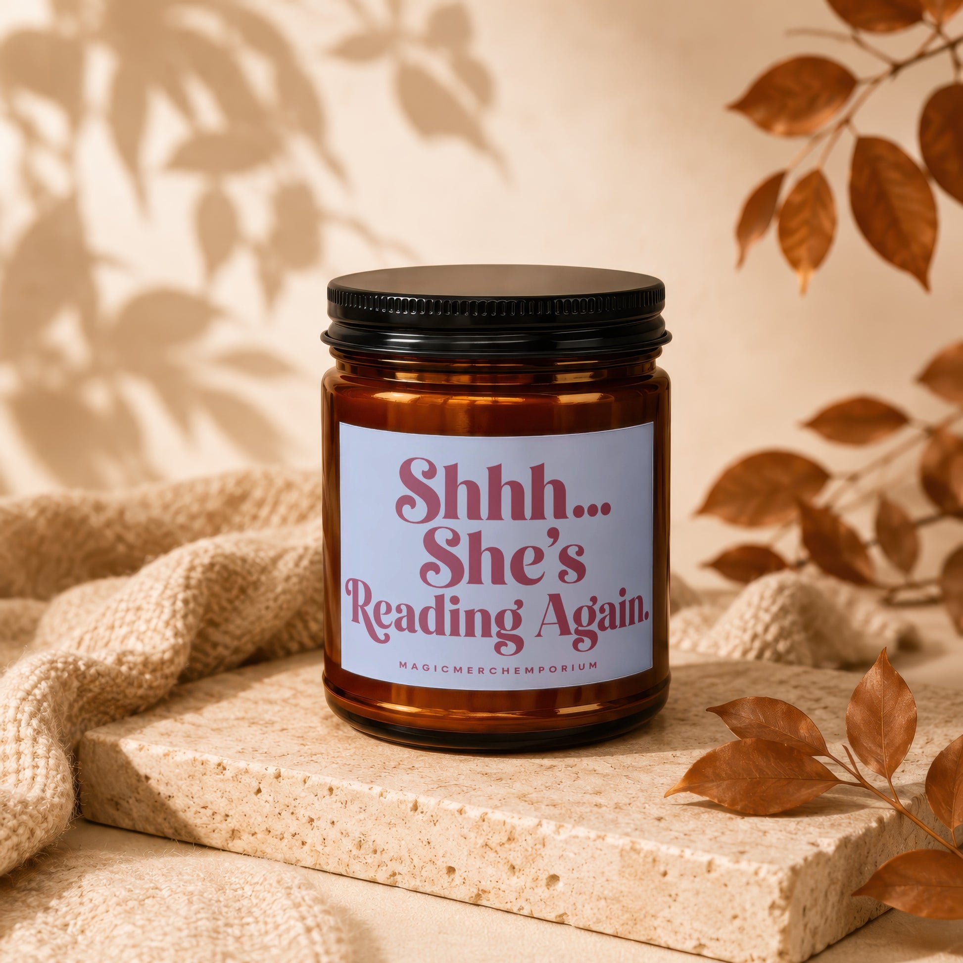 Amber candle with black lid and label that reads "Shhh... She's Reading Again."