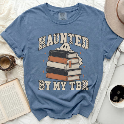 T-shirt with a ghost peeking over books, text reads "Haunted by my TBR".