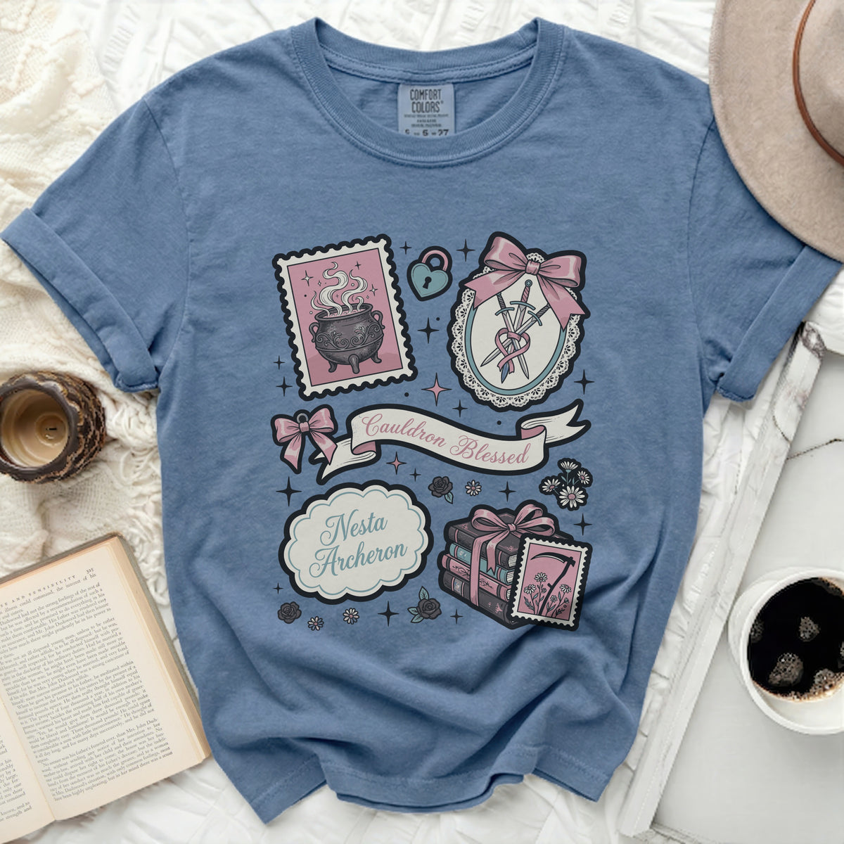 Blue t-shirt with whimsical witchy and bookish design elements and text.