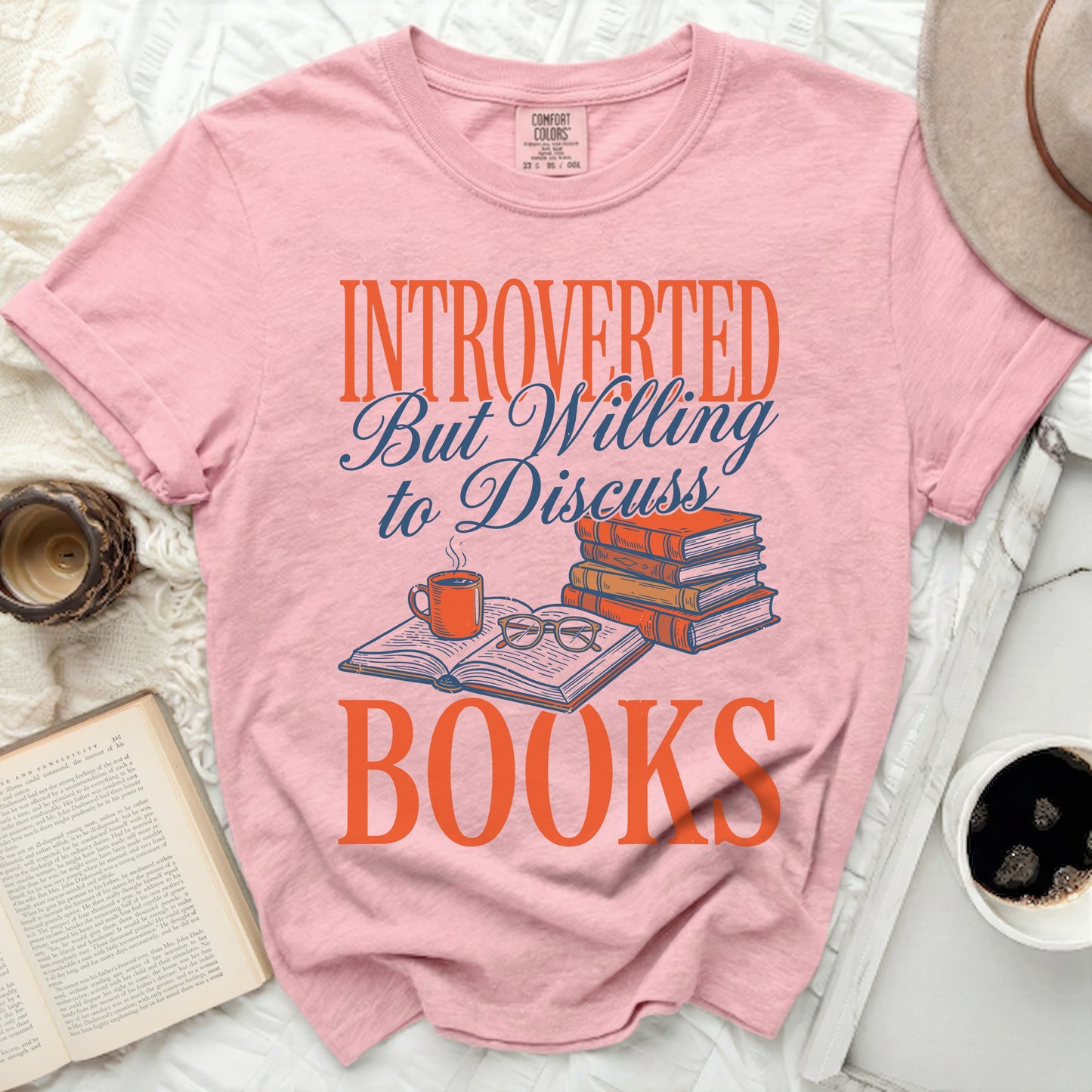 Pink t-shirt with text "INTROVERTED to Discuss BOOKS" and stack of books.