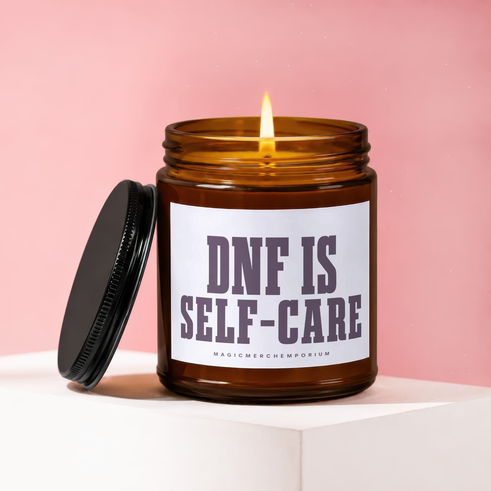 Amber candle with lit flame, black lid. Text: DNF IS SELF-CARE.