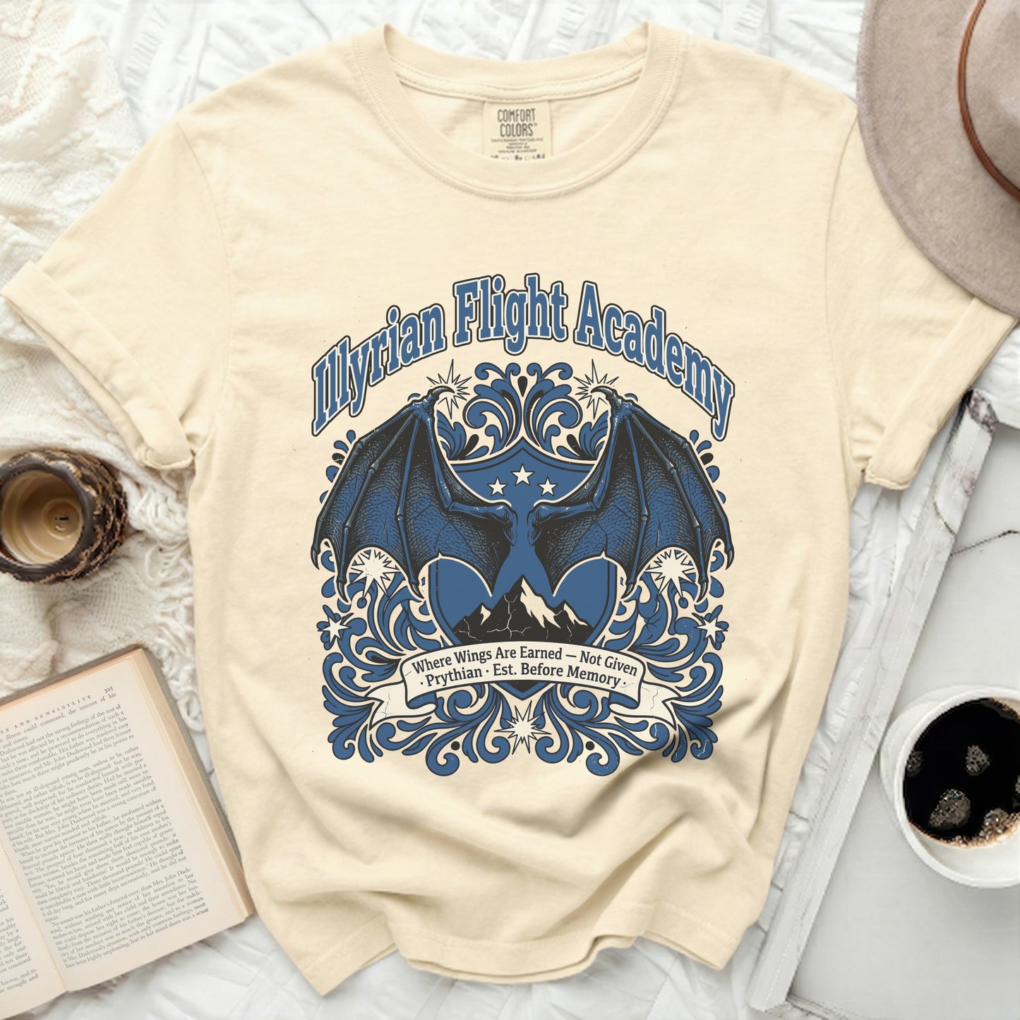 Cream t-shirt with blue "Illyrian Flight Academy" graphic and dragon wings.
