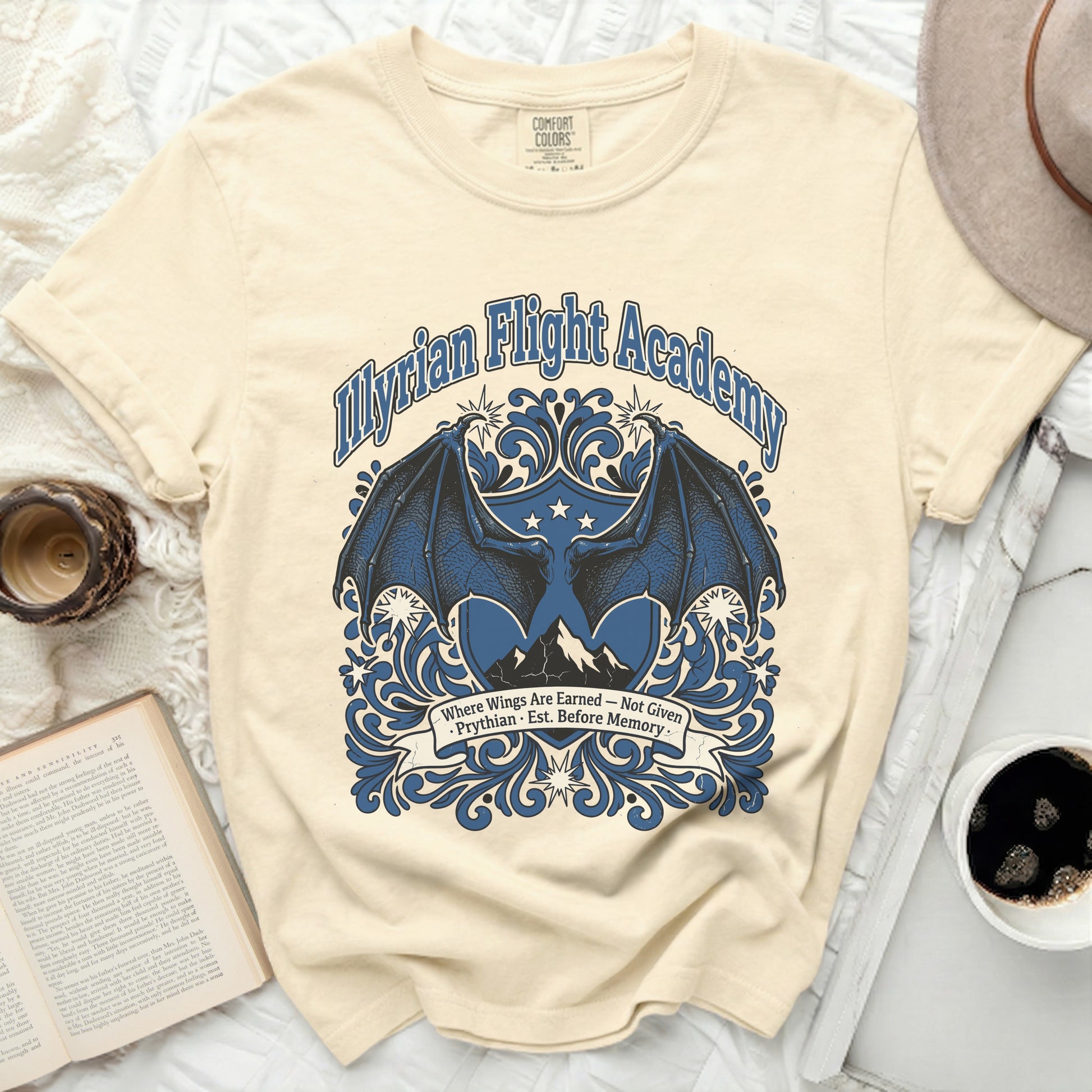 Cream t-shirt with blue "Illyrian Flight Academy" graphic and dragon wings.