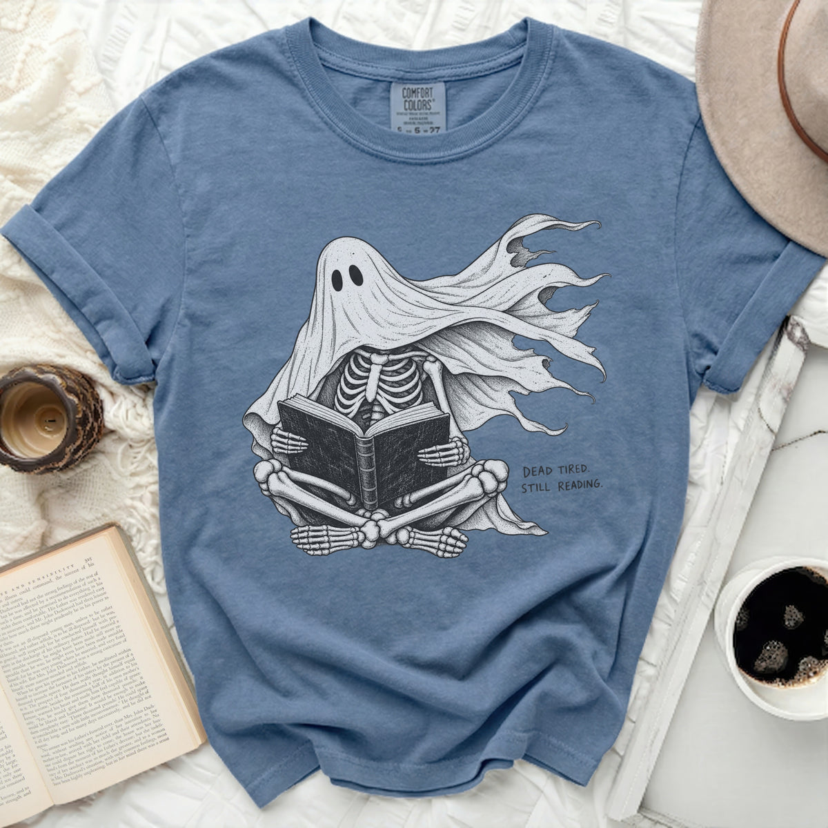 Skeleton ghost in a sheet reading a book, text reads "DEAD TIRED. STILL READING."