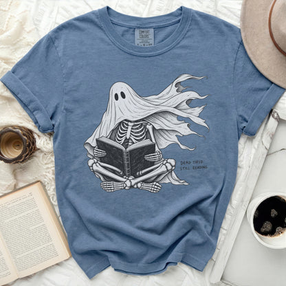 Skeleton ghost in a sheet reading a book, text reads "DEAD TIRED. STILL READING."